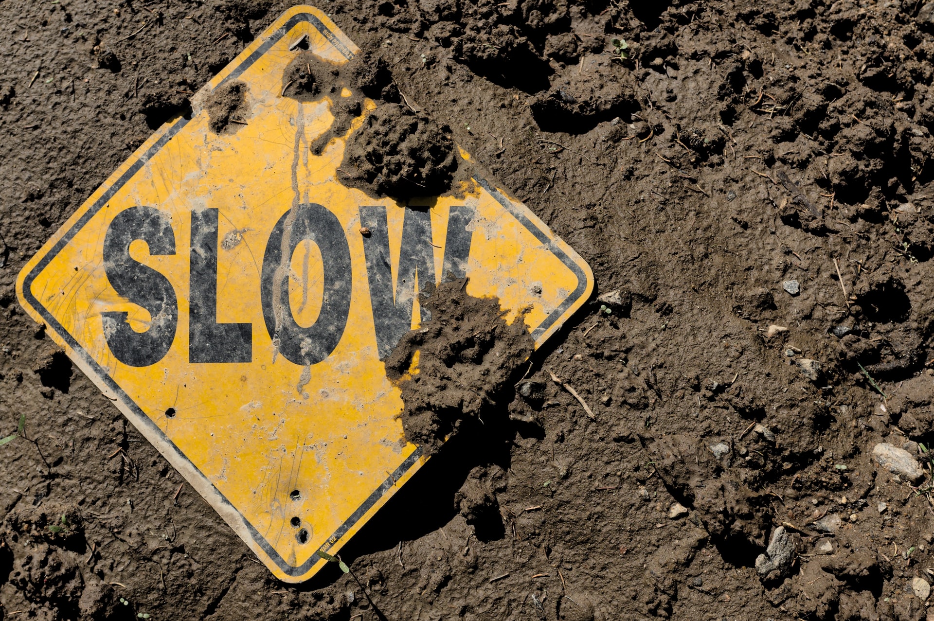 yellow slow caution sign in dirt reminding to dance the slow steps